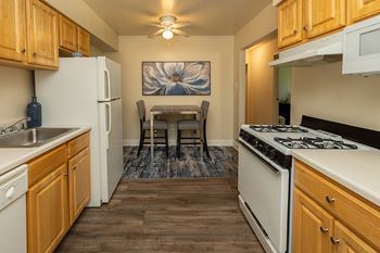A kitchen with wooden cabinets and a white stove top oven.at Deer Park Apartments, Randallstown, MD